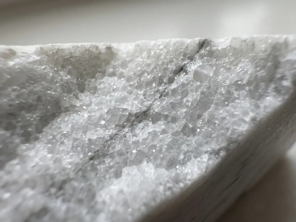 Broken edge of a white marble seen up close: calcite crystals fitted together like a mosaic