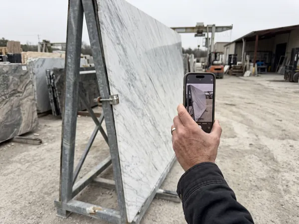 A hand photographs a marble slab with a phone