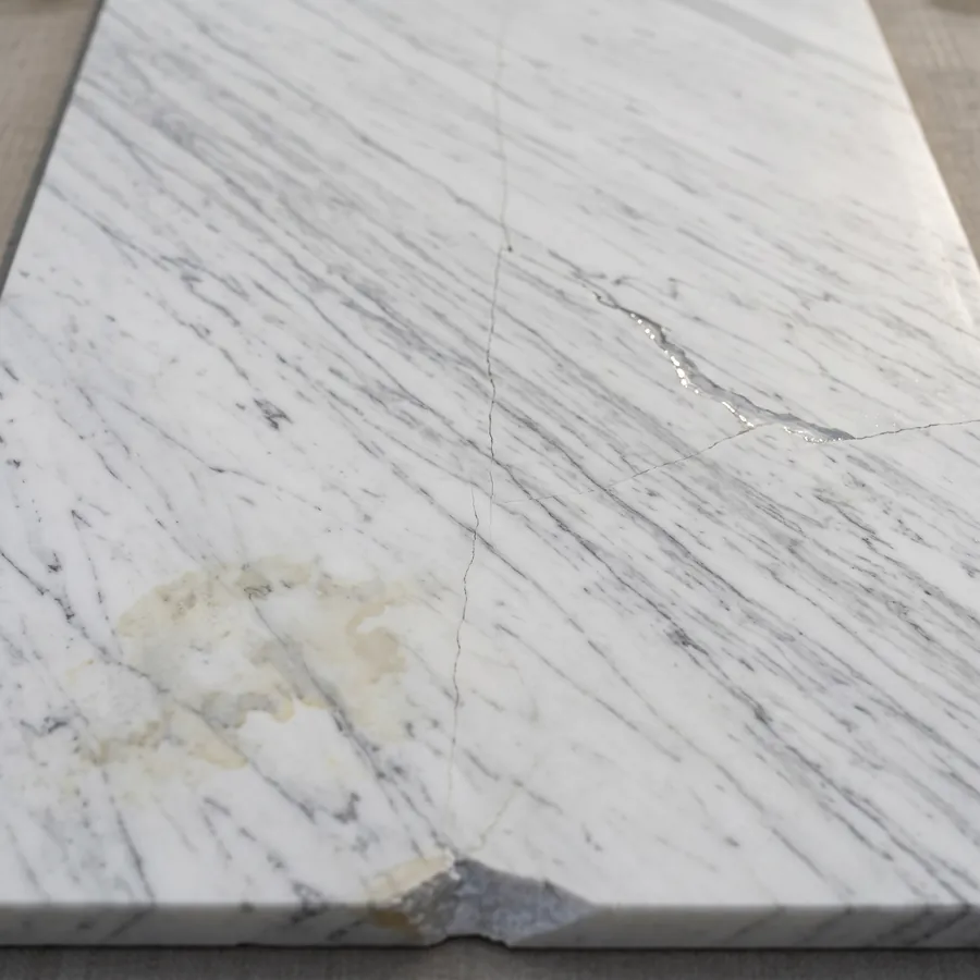 Second-choice Carrara marble slab with fissures, a resin-filled crack, a stain and a chipped corner