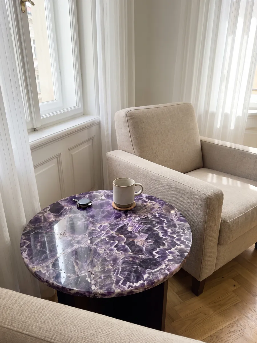 Side table with an amethyst top next to an armchair: dark violet crystals with white and lilac zigzag bands
