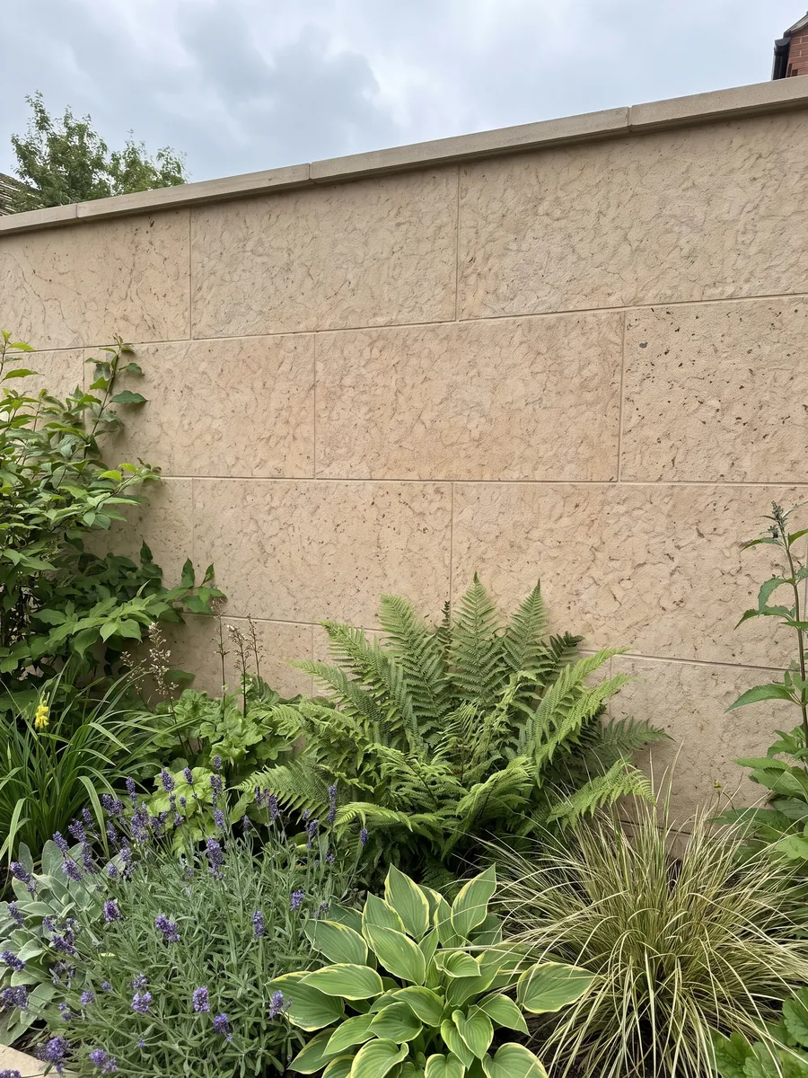 Garden wall clad in Santafiora Fiorita sandstone with plants in front: sandy beige with a network pattern of patches, like a fine crackling