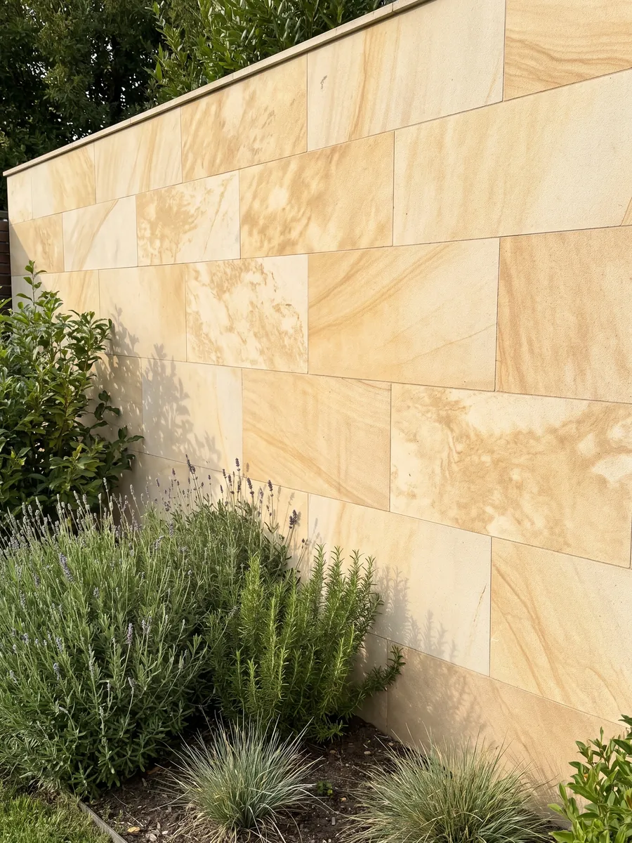 Garden wall clad in Santafiora Havana sandstone with plants in front: warm cream tone with diffuse golden clouds and a soft sandy texture