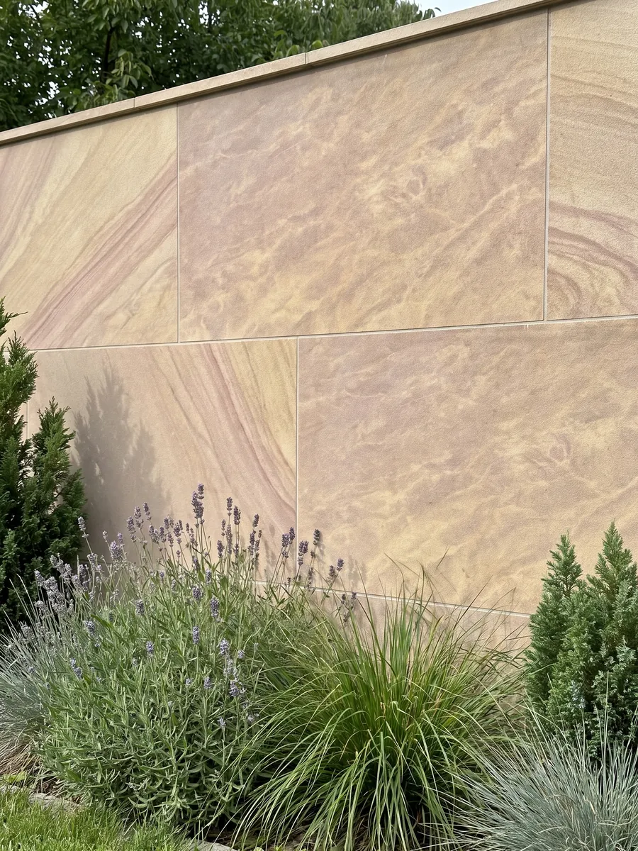 Garden wall clad in Santafiora Venata sandstone with plants in front: sandy beige with soft diagonal waves, like sand dunes