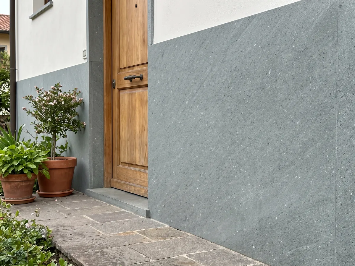 House facade clad in Basaltite basalt next to a wooden door: very uniform fine-grained greenish gray with isolated white specks