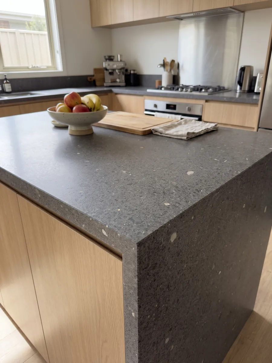 Kitchen island with a Lavagrigia basalt countertop and a straight edge in a naturally lit kitchen: granular salt and pepper purplish gray with scattered white inclusions