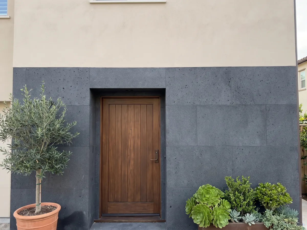 House facade clad in Pietra Lavica basalt next to a wooden door: almost black gray, uniform and very fine-grained