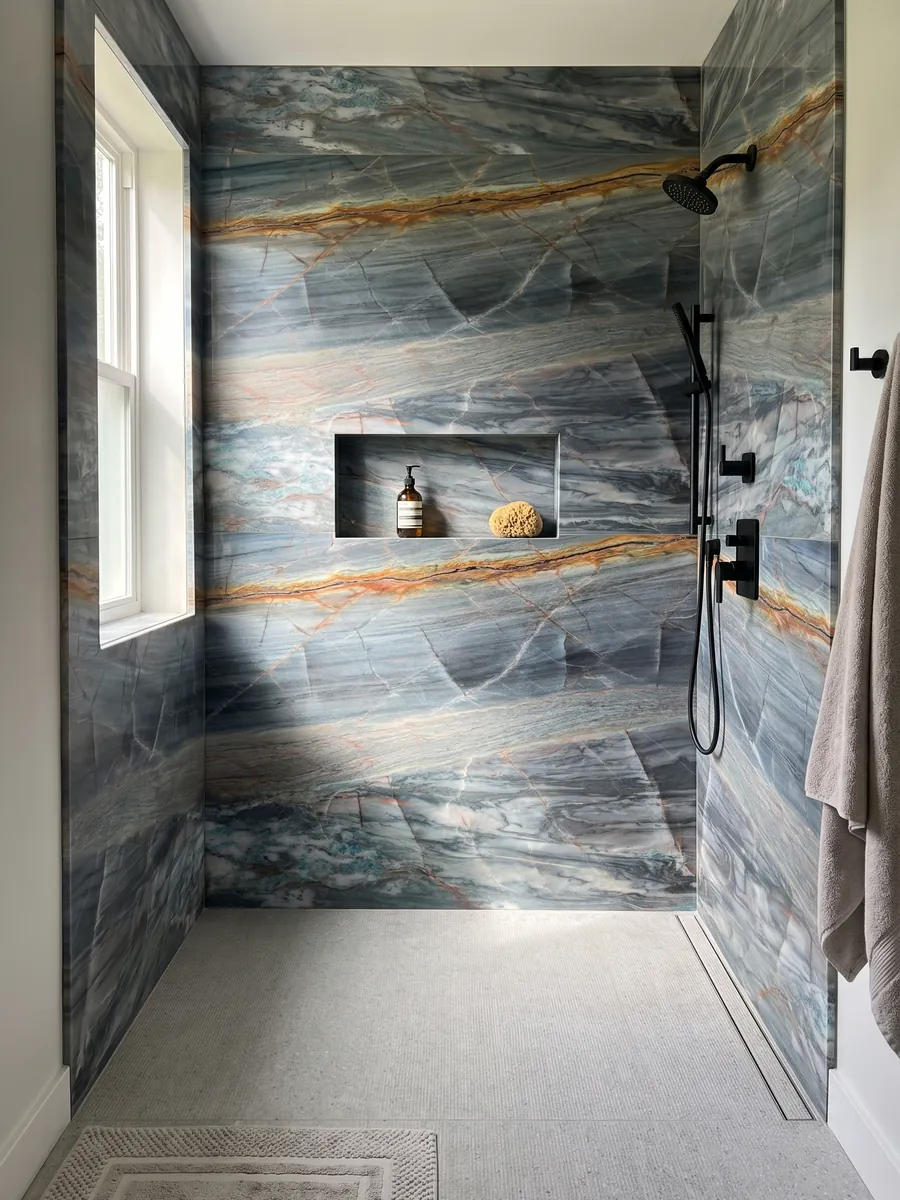 Shower clad in full Blue Atlantic quartzite slabs with a recessed niche: grayish blue in horizontal bands with a strong orange vein on top