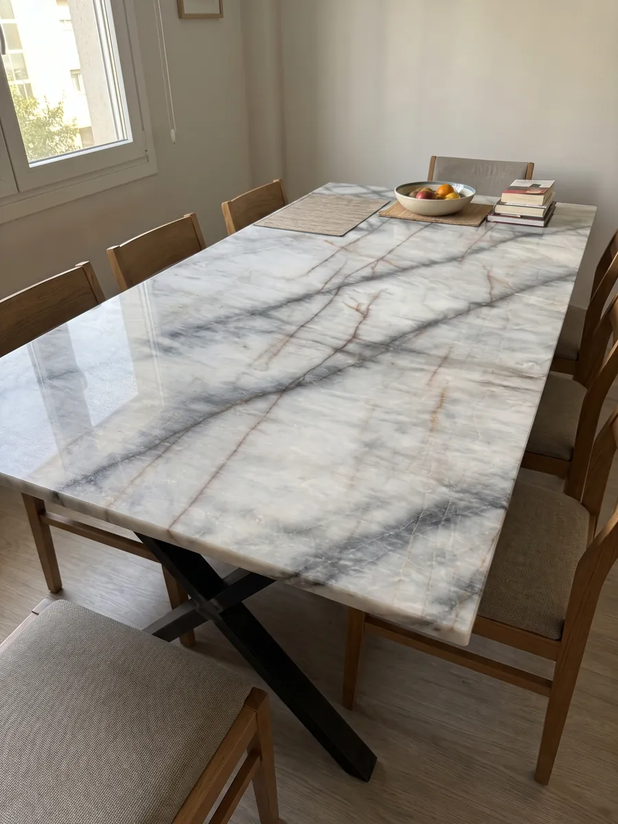 Dining table with a white Cristallo Black quartzite top on a steel base: white with soft dark diagonal veins and thin orange lines