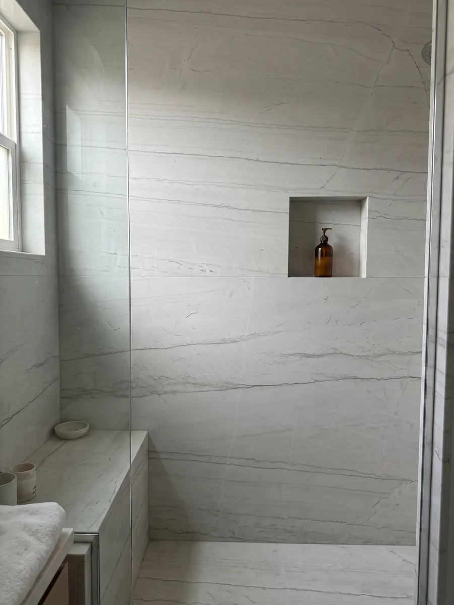Shower clad in full Mont Blanc white quartzite slabs with a recessed niche: nearly clean white with two or three very fine gray lines