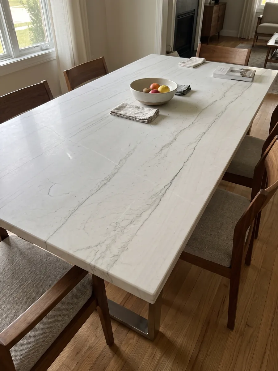 Dining table with a Mont Blanc white quartzite top on a steel base: nearly clean white with two or three very fine gray lines