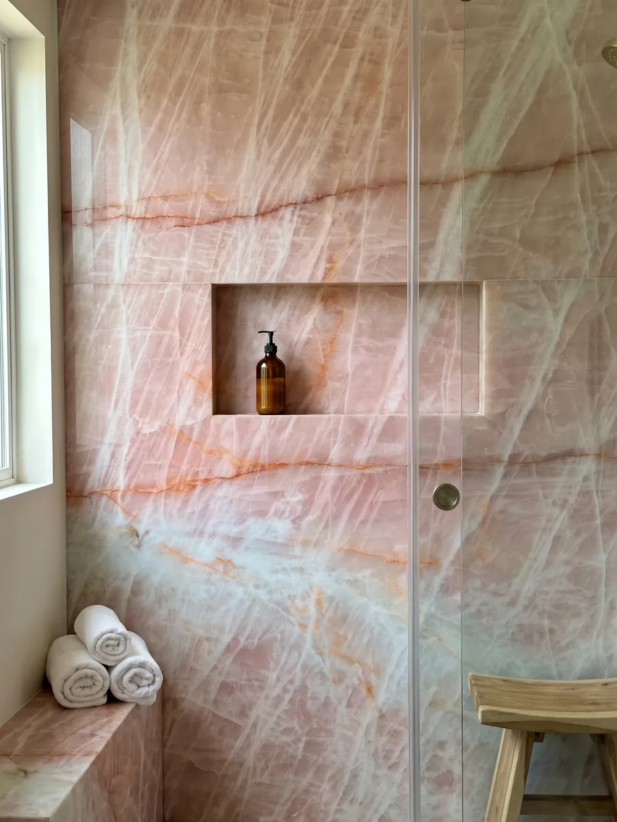 Shower clad in full Cristallo Rosa quartzite slabs with a recessed niche: salmon pink with horizontal orange veins and a light blue area at the bottom