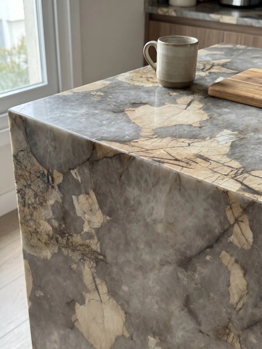 Straight edge of a gray Patagonia quartzite kitchen countertop with the vein continuing over the edge: cloudy gray with large irregular beige patches and fine dark lines