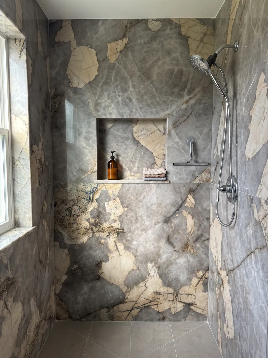 Shower clad in full gray Patagonia quartzite slabs with a recessed niche: cloudy gray with large irregular beige patches and fine dark lines