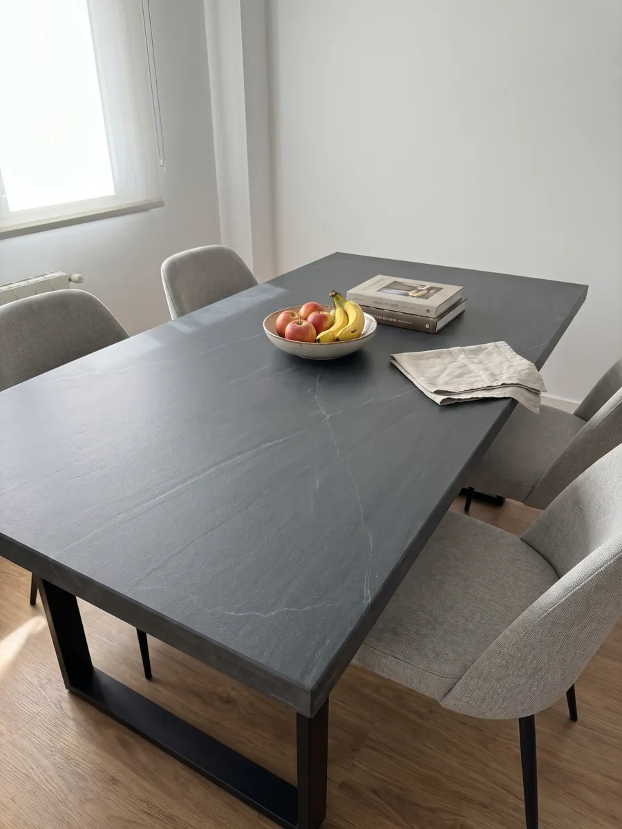 Dining table with a gray Pietra del Cardoso quartzite top on a steel base: uniform dark slate gray, no pattern