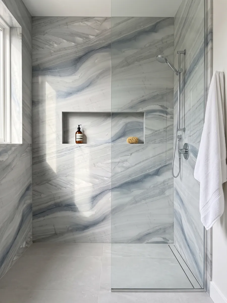 Shower clad in full gray Polaris quartzite slabs with a recessed niche: light gray with soft blue-gray waves running diagonally