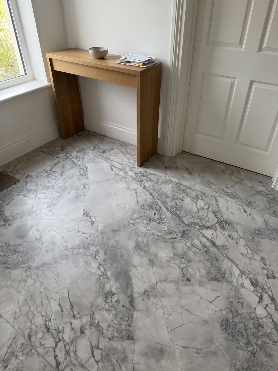 Entryway floor in large slabs of gray Super White quartzite with natural light: light gray with a network of slightly darker gray veins