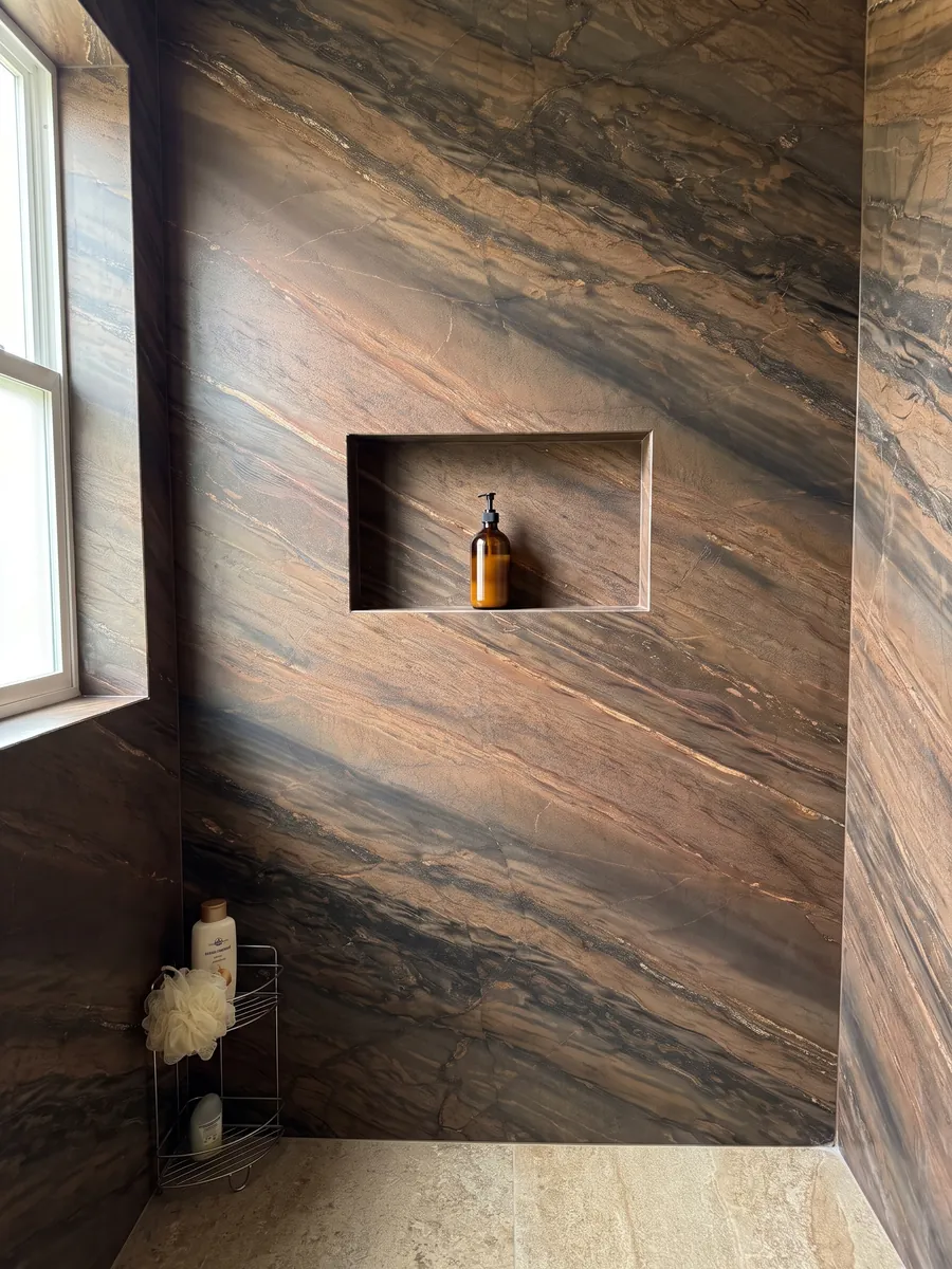 Shower clad in full slabs of Elegant Brown quartzite with a recessed niche: coppery brown in parallel diagonal bands with fine gold lines