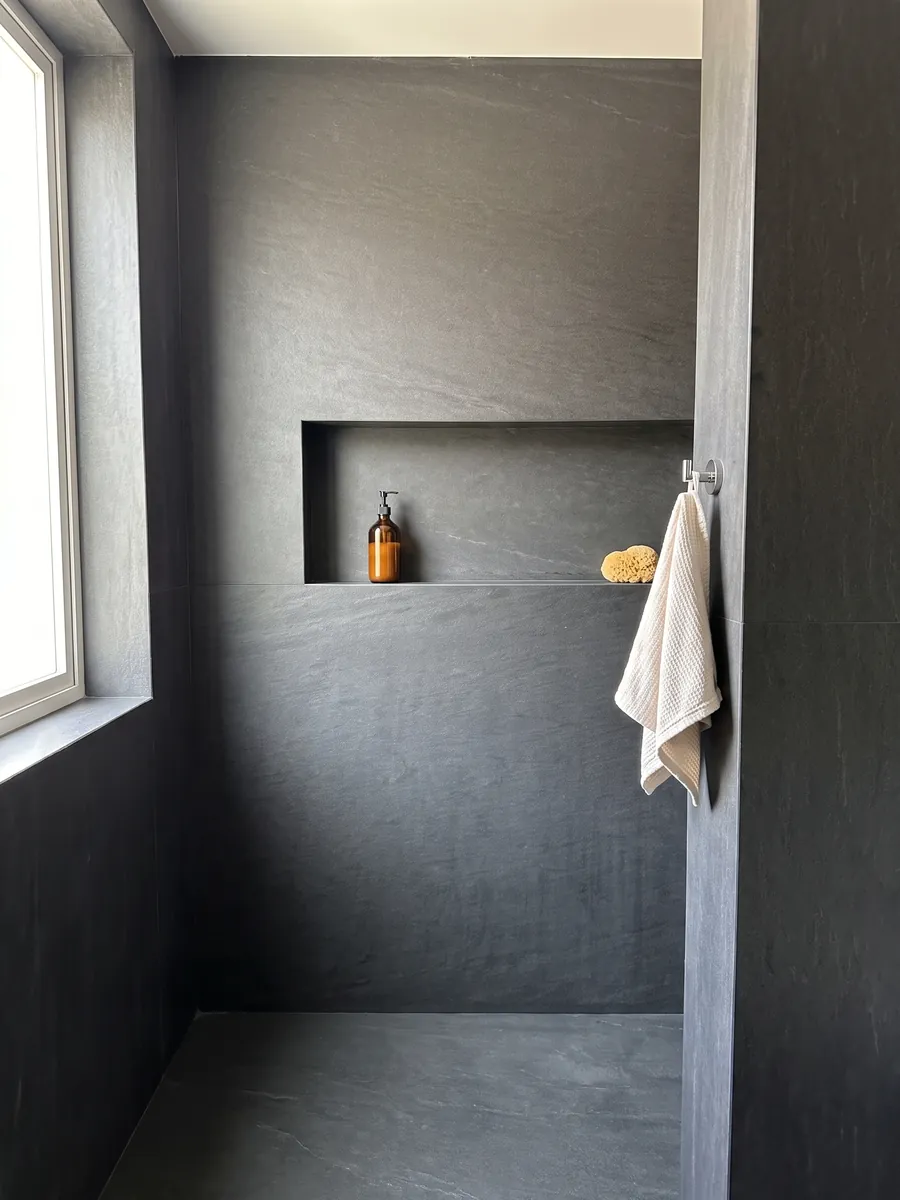 Shower clad in full Black Vermont quartzite slabs with a recessed niche: nearly uniform anthracite gray with no visible pattern