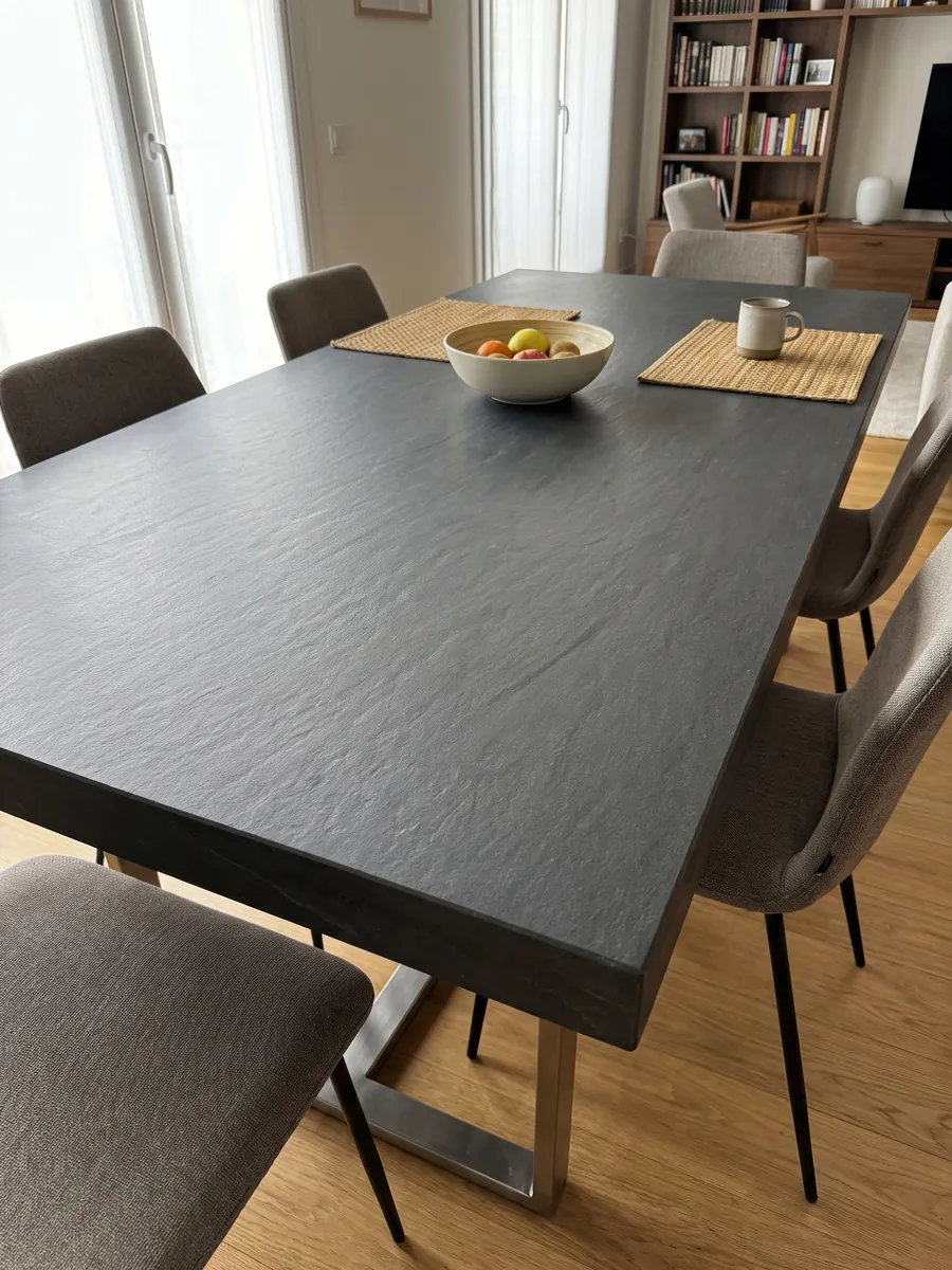 Dining table with a Black Vermont quartzite top on a steel base: nearly uniform anthracite gray with no visible pattern