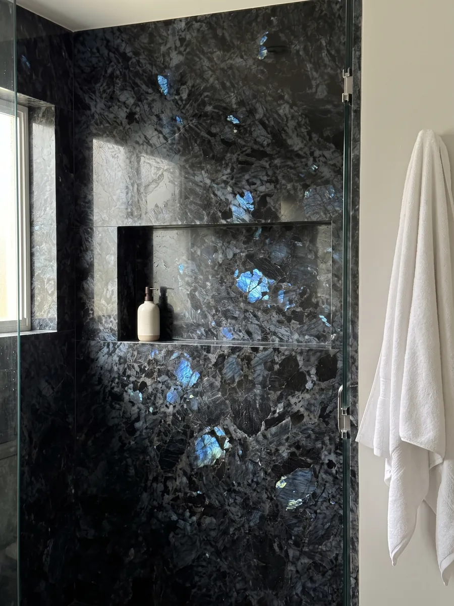 Shower clad in full Lemurian black quartzite slabs with a recessed niche: black with large crystals and flashes of iridescent blue