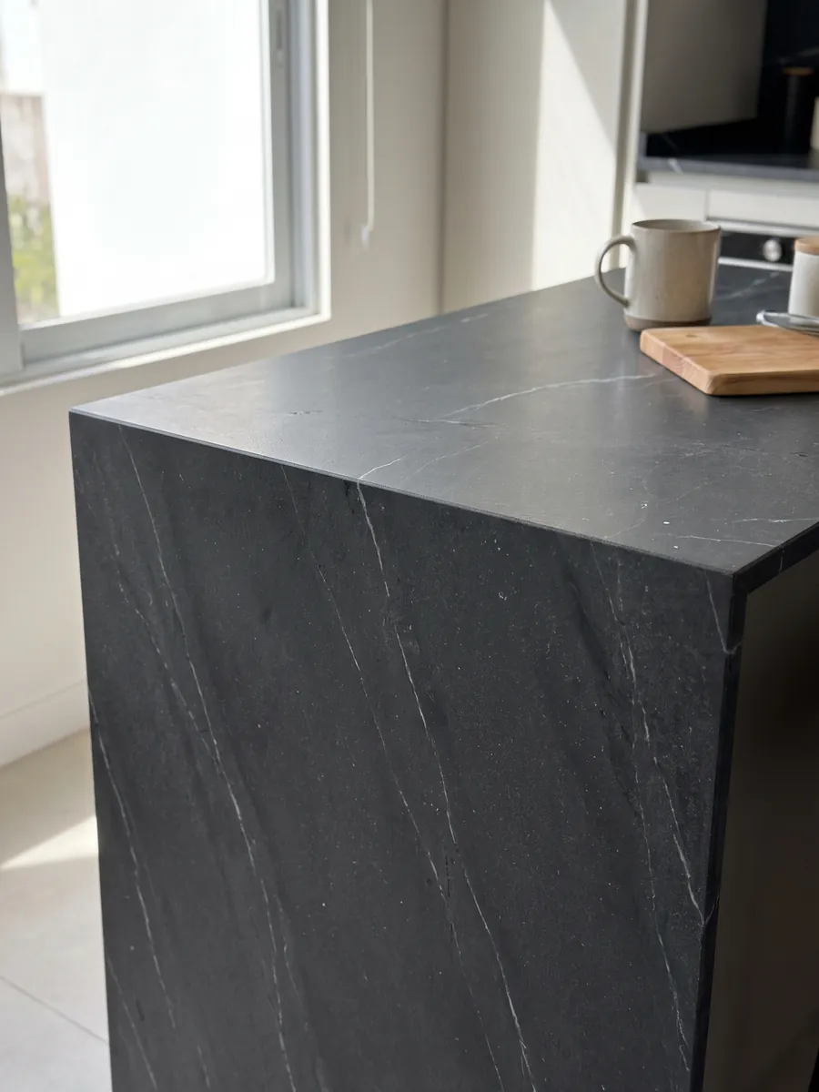 Straight edge of a Negresco black quartzite kitchen countertop with the vein continuing over the edge: black with fine, sparse white veins running diagonally