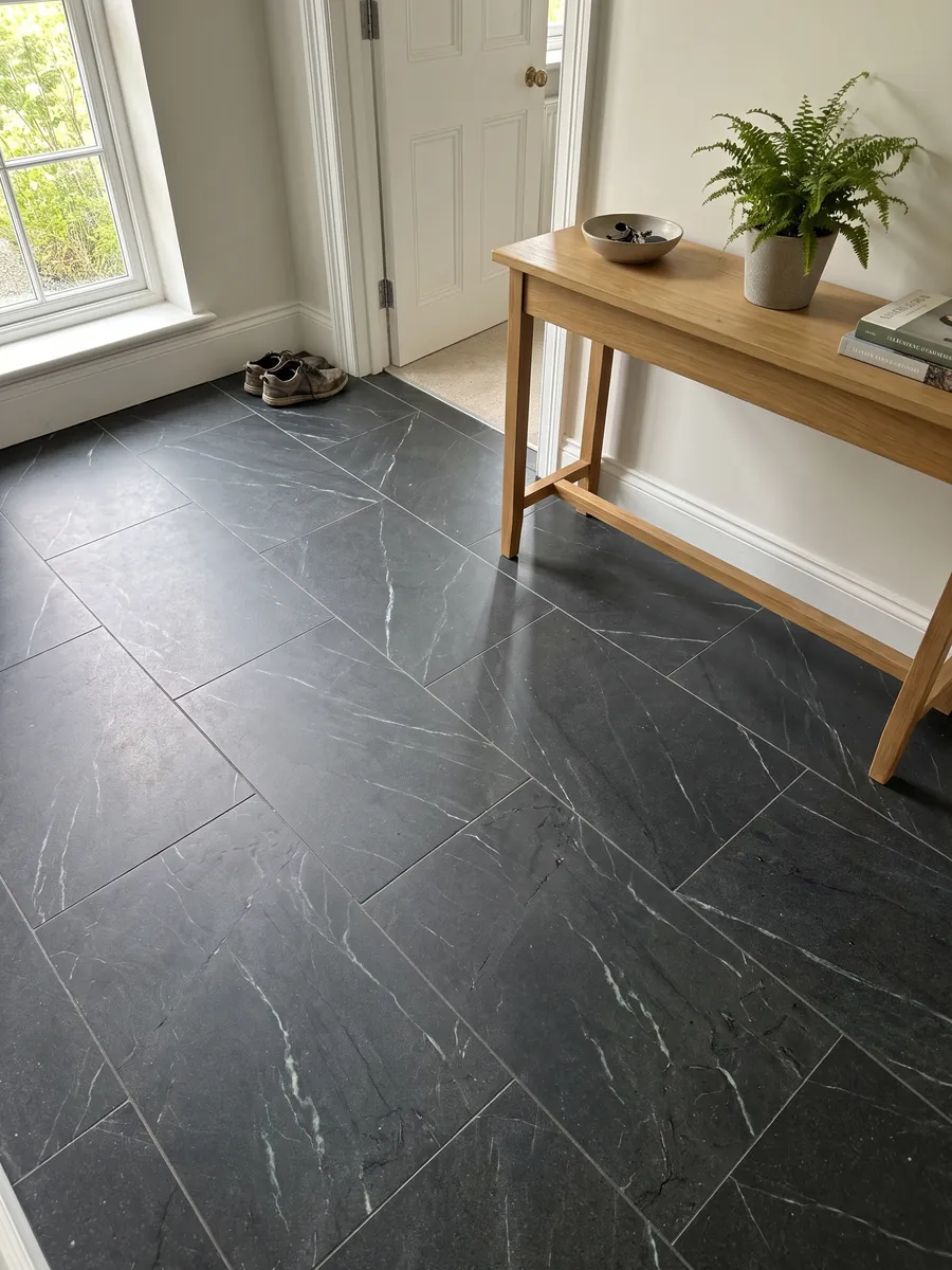 Entryway floor in large Negresco black quartzite slabs with natural light: black with fine, sparse white veins running diagonally