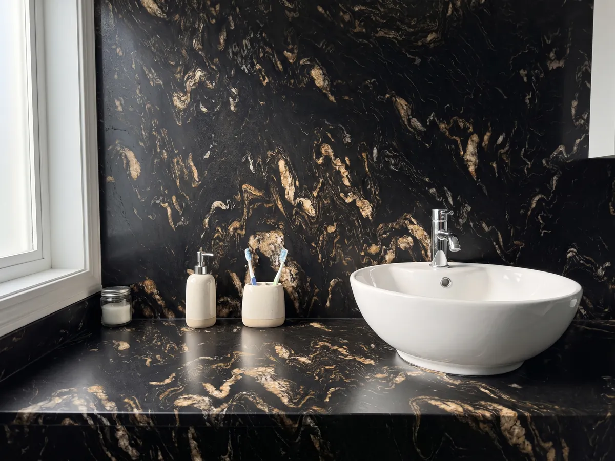 Vanity top and bathroom wall in black Titanium quartzite with a white sink and chrome fittings: black with golden and beige flame-shaped inclusions
