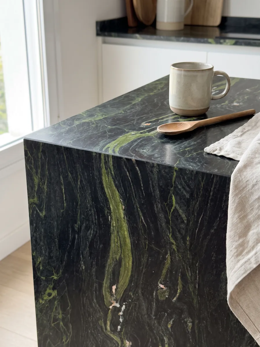 Straight edge of a kitchen countertop in Vancouver black quartzite with the vein running over the edge: greenish black with horizontal lime green waves