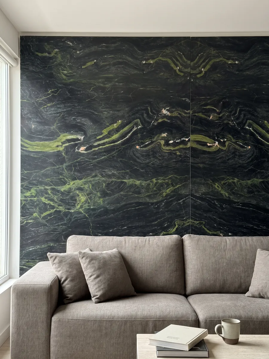 Living room wall clad with bookmatched Vancouver black quartzite slabs behind a sofa: greenish black with horizontal lime green waves
