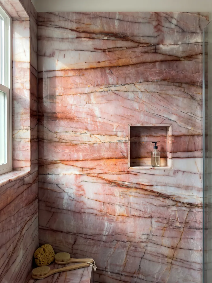 Shower clad in full pink Juliet quartzite slabs with a recessed niche: intense pink and white with horizontal rust red veins