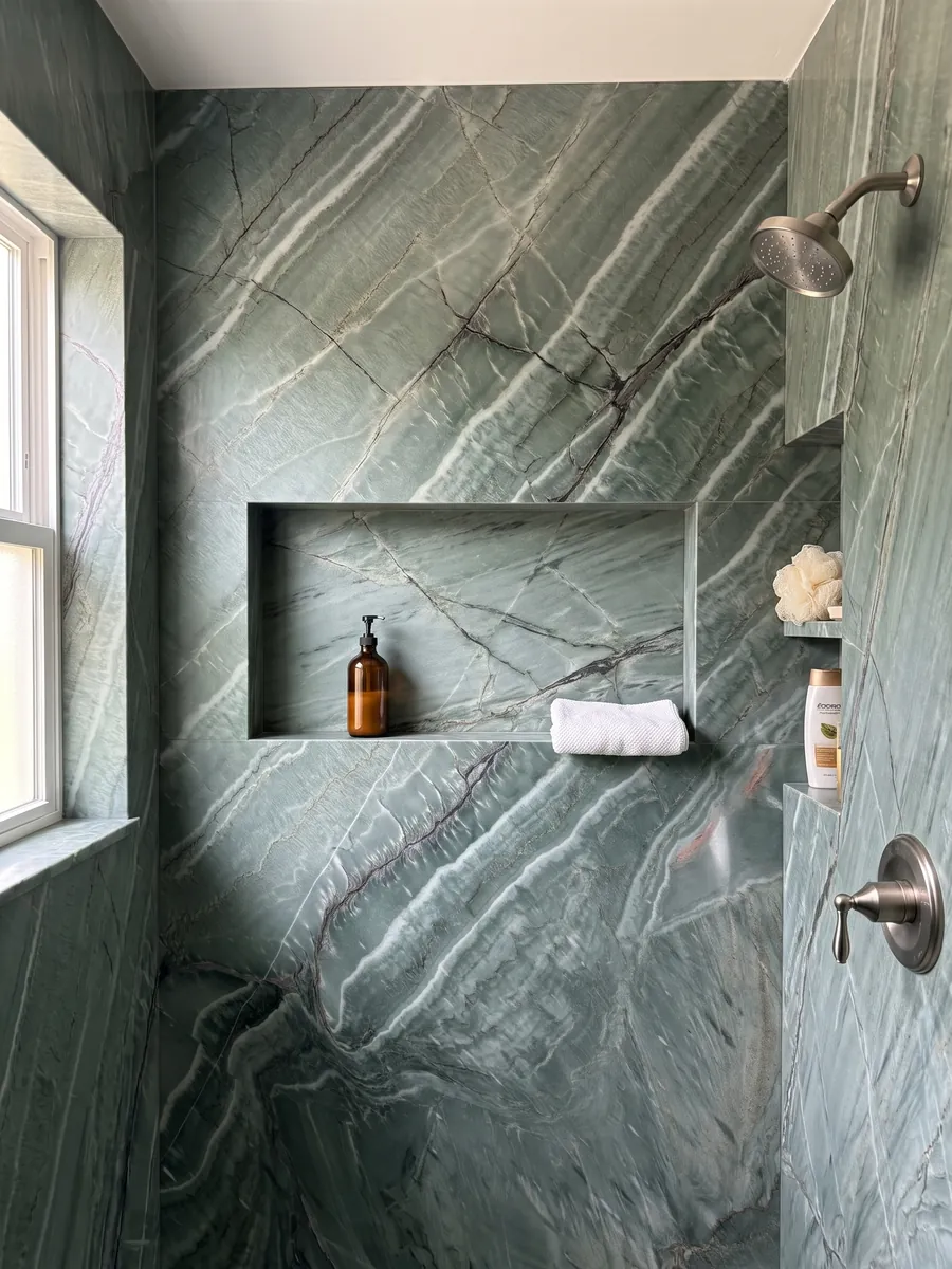 Shower clad in full green Amazzonia Green quartzite slabs with a recessed niche: jade green with diagonal white waves and crossing dark veins