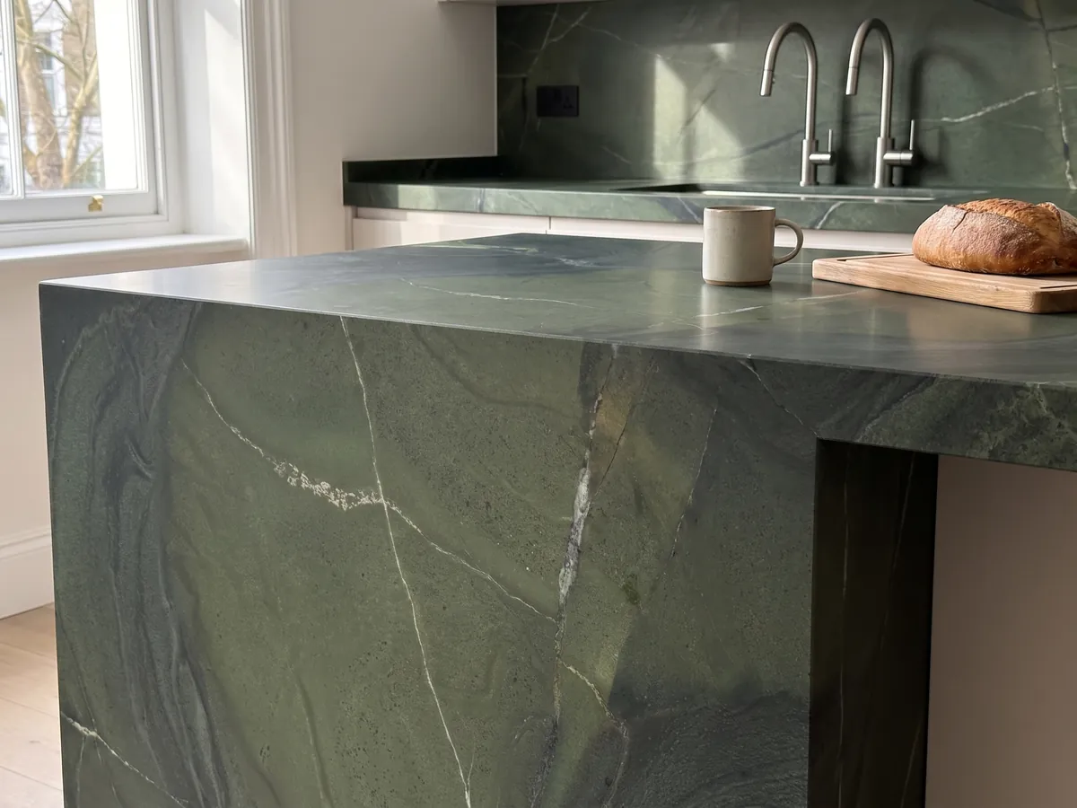 Kitchen island with a green Avocatus quartzite countertop and a straight edge in a naturally lit kitchen: deep green in areas, crossed by a few fine white lines