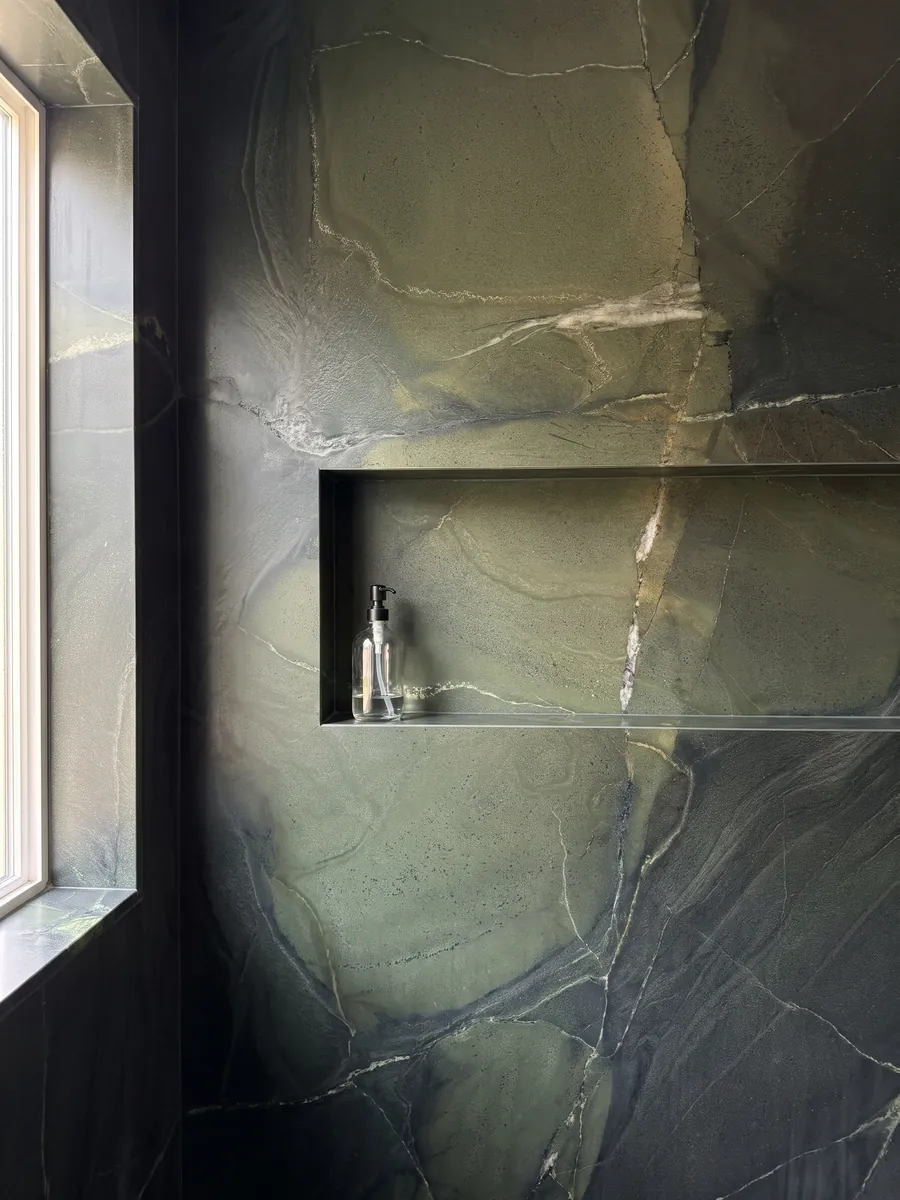 Shower clad in full green Avocatus quartzite slabs with a recessed niche: deep green in areas, crossed by a few fine white lines