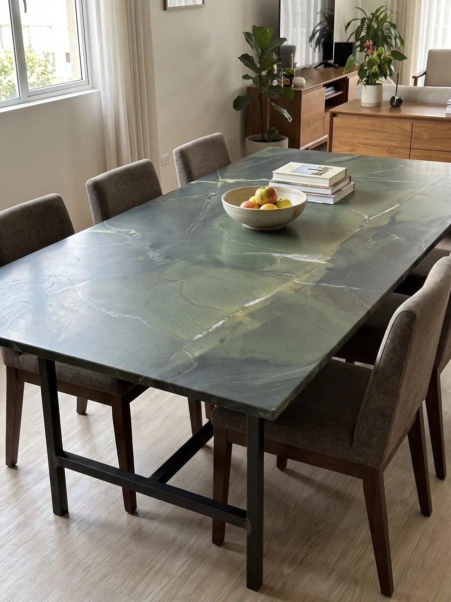 Dining table with a green Avocatus quartzite top on a steel base: deep green in areas, crossed by a few fine white lines