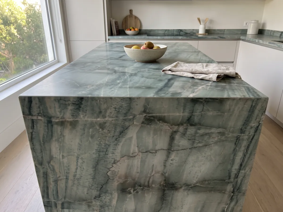 Kitchen island with a green Da Vinci quartzite countertop and a straight edge in a kitchen with natural light: grayish green with a grid of dark vertical veins and light bands