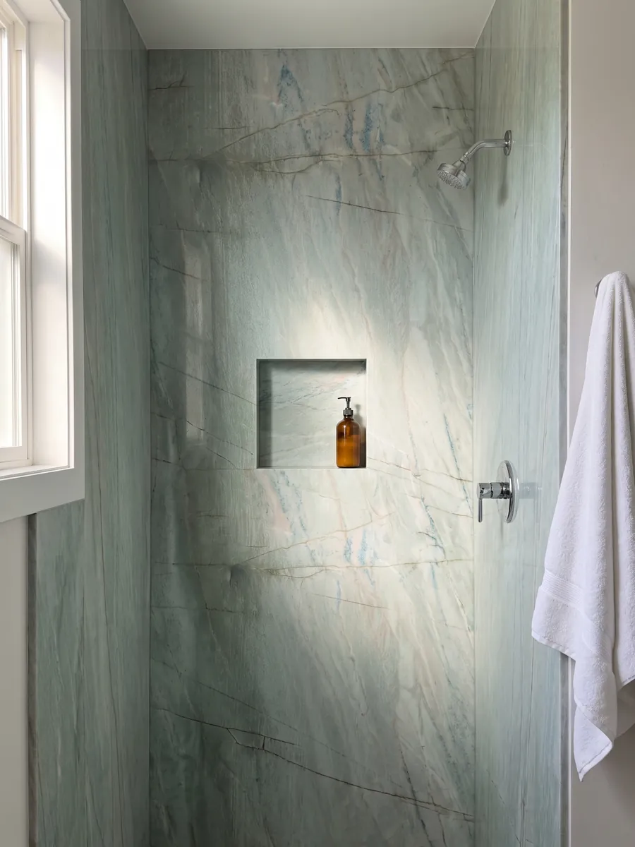 Shower clad in full slabs of Emerald Green quartzite with a recessed niche: light sea green with fine vertical dark lines and small blue glints