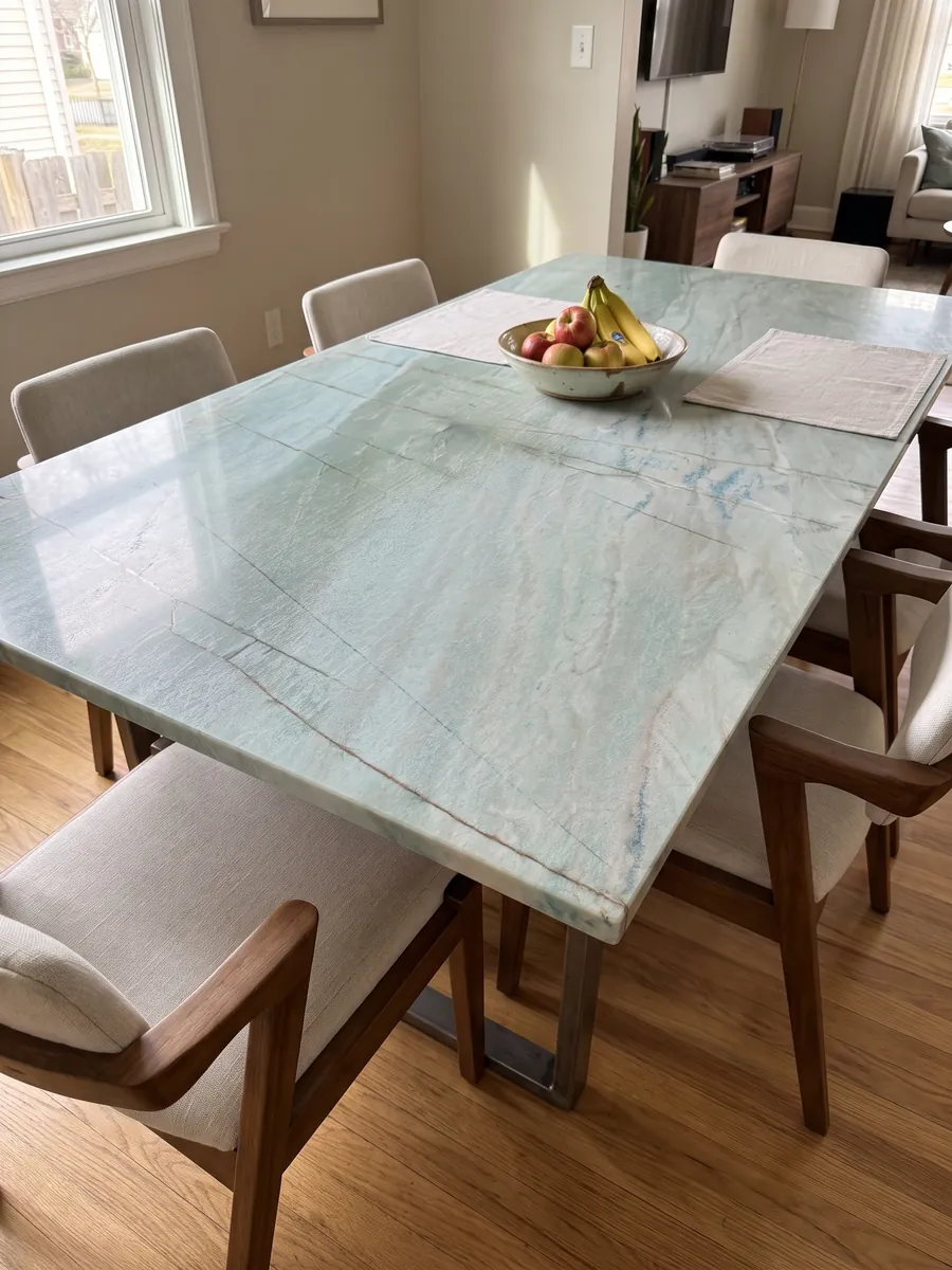 Dining table with an Emerald Green quartzite top on a steel base: light sea green with fine vertical dark lines and small blue glints