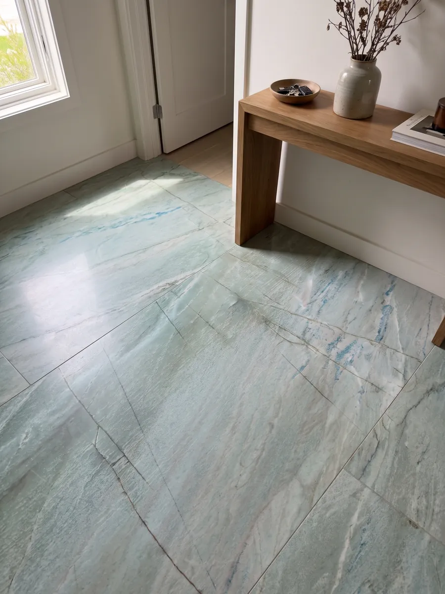 Entryway floor in large slabs of Emerald Green quartzite with natural light: light sea green with fine vertical dark lines and small blue glints