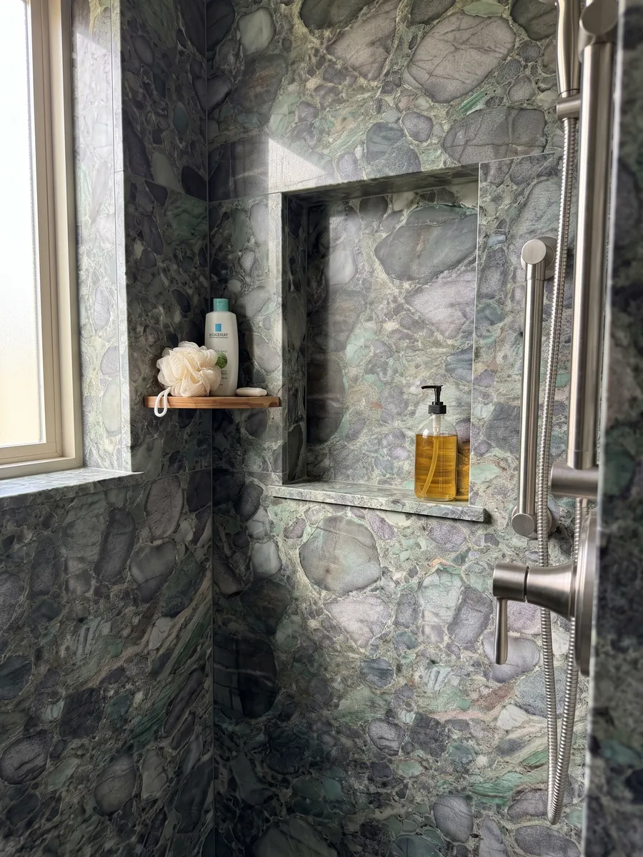 Shower clad in full Palladium Green quartzite slabs with a recessed niche: rounded violet-gray clasts with a green matrix and emerald glints