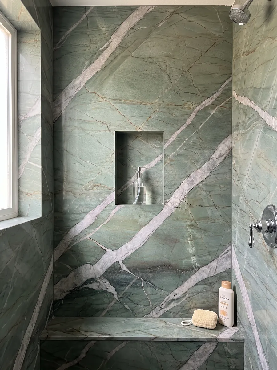 Shower clad in full green Patagonia Green quartzite slabs with a recessed niche: jade green crossed by wide light gray veins on the diagonal