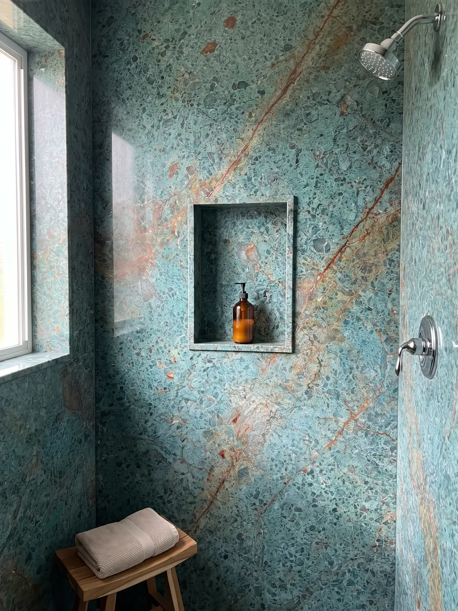 Shower clad in full slabs of green Tanzanite quartzite with a recessed niche: speckled turquoise crossed by a diagonal rust red band