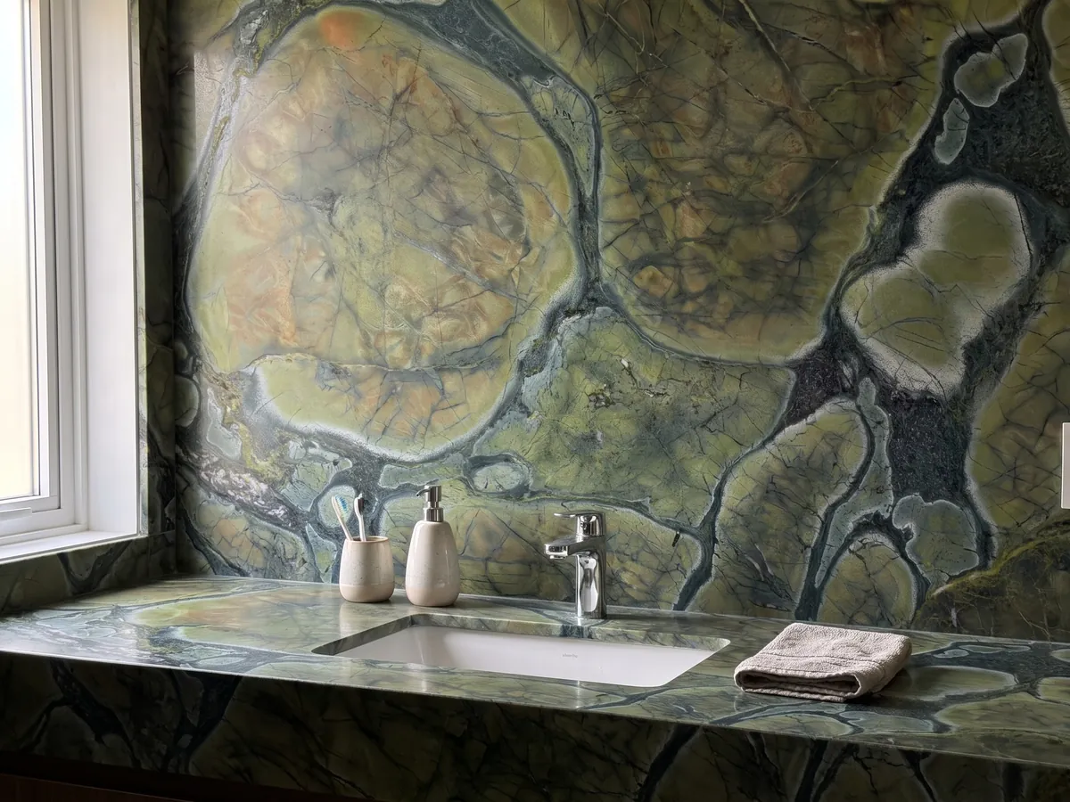 Bathroom vanity top and wall in green Victoria Regia quartzite with a white sink and chrome faucet: rounded olive green cells with dark edges, like lily pads