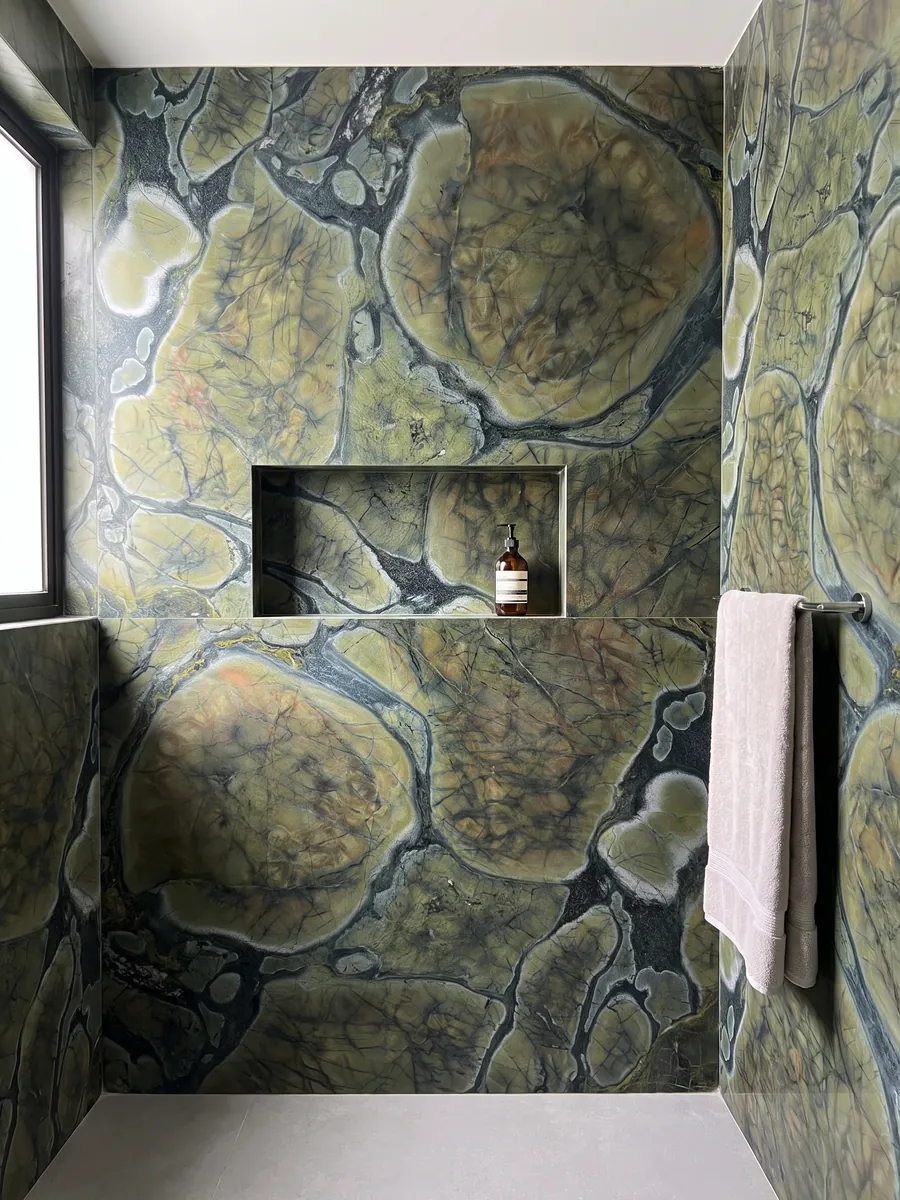 Shower clad in full green Victoria Regia quartzite slabs with a recessed niche: rounded olive green cells with dark edges, like lily pads