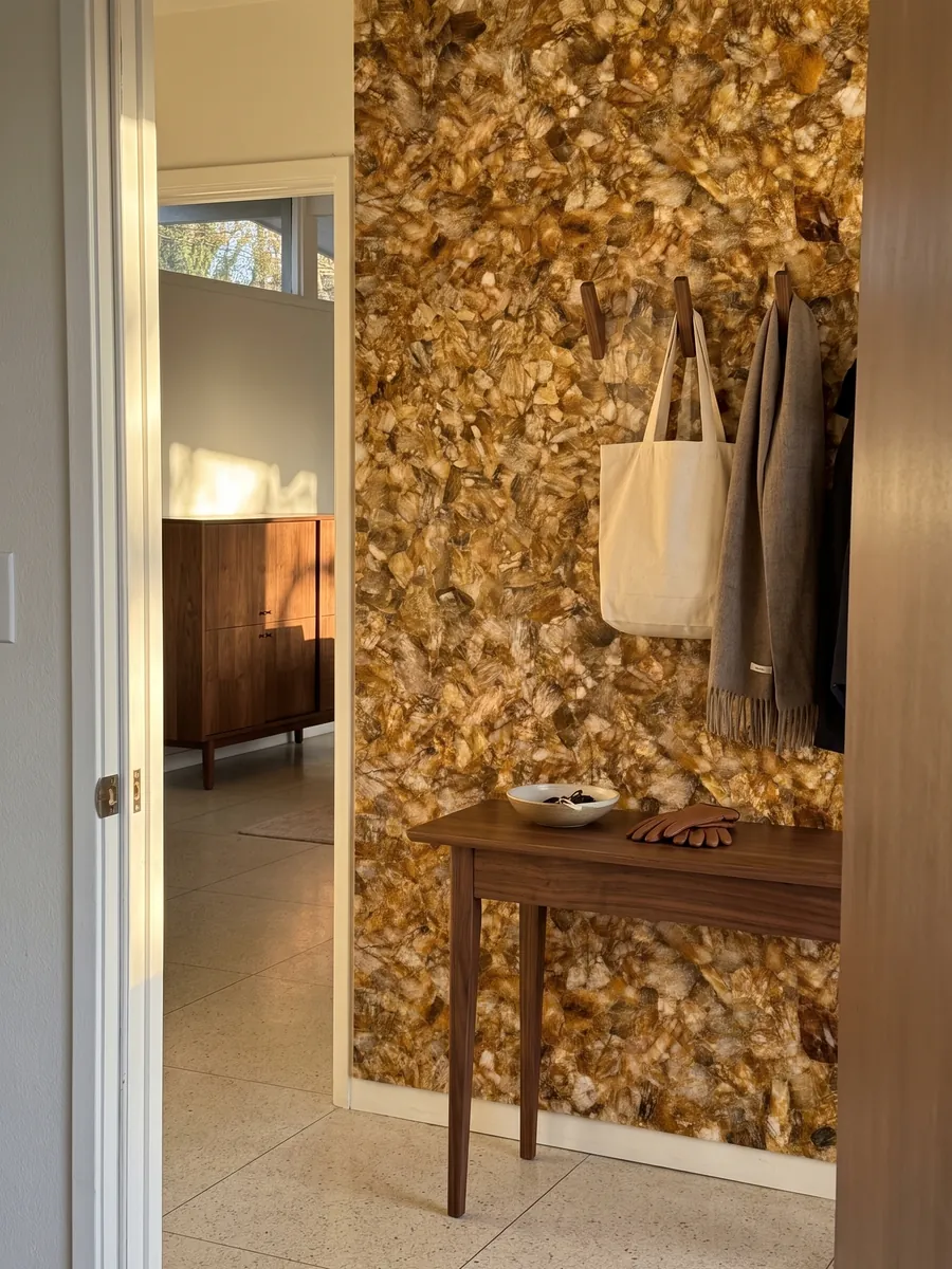 Entryway wall clad in lemon quartz with a narrow console: tightly packed honey and cream glassy fragments