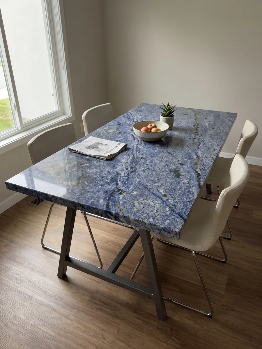 Dining table with an Azul Bahia Granite top on a steel base: deep granular blue with white areas and dark patches