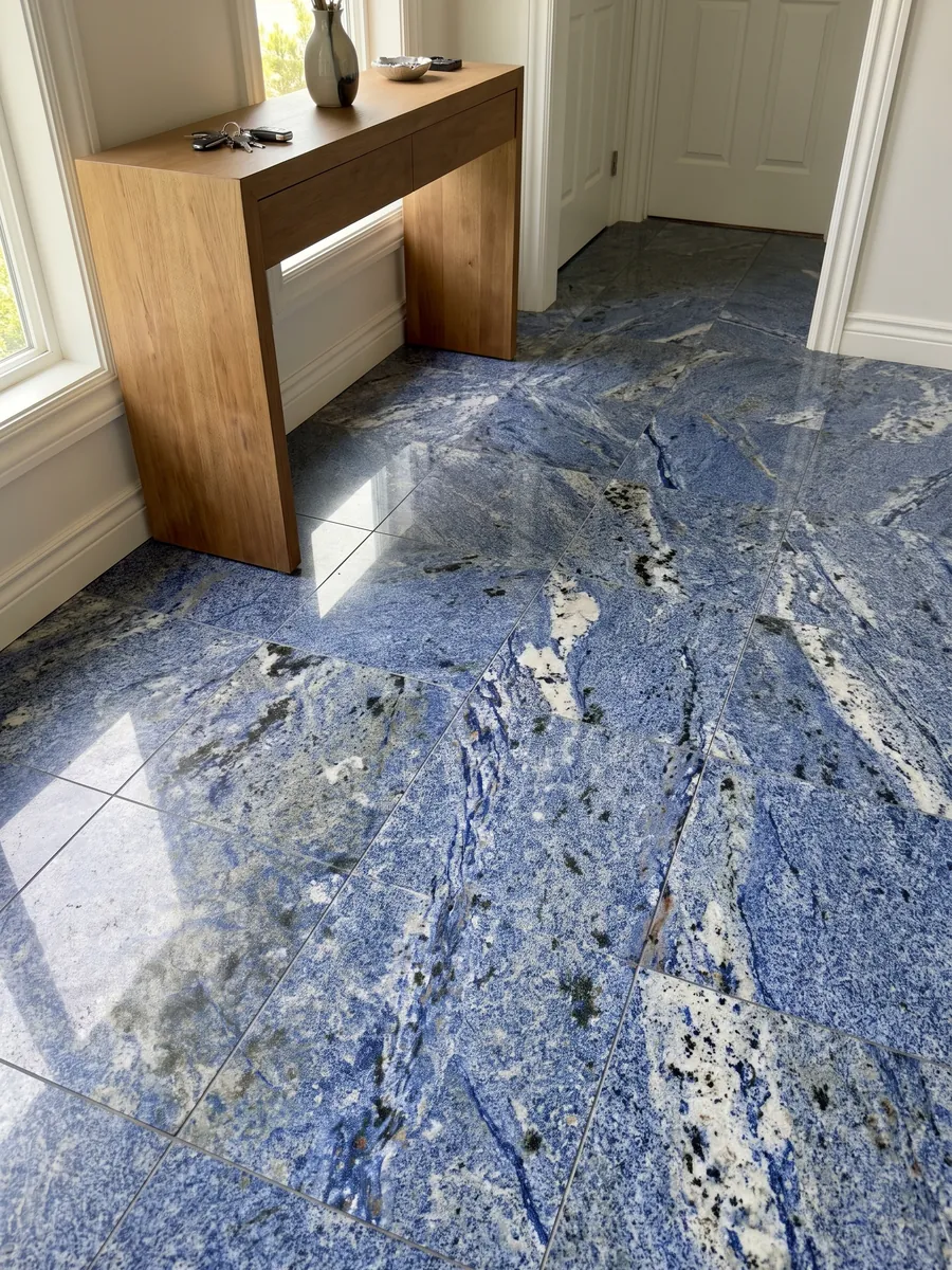 Entryway floor in large Azul Bahia Granite slabs with natural light: deep granular blue with white areas and dark patches
