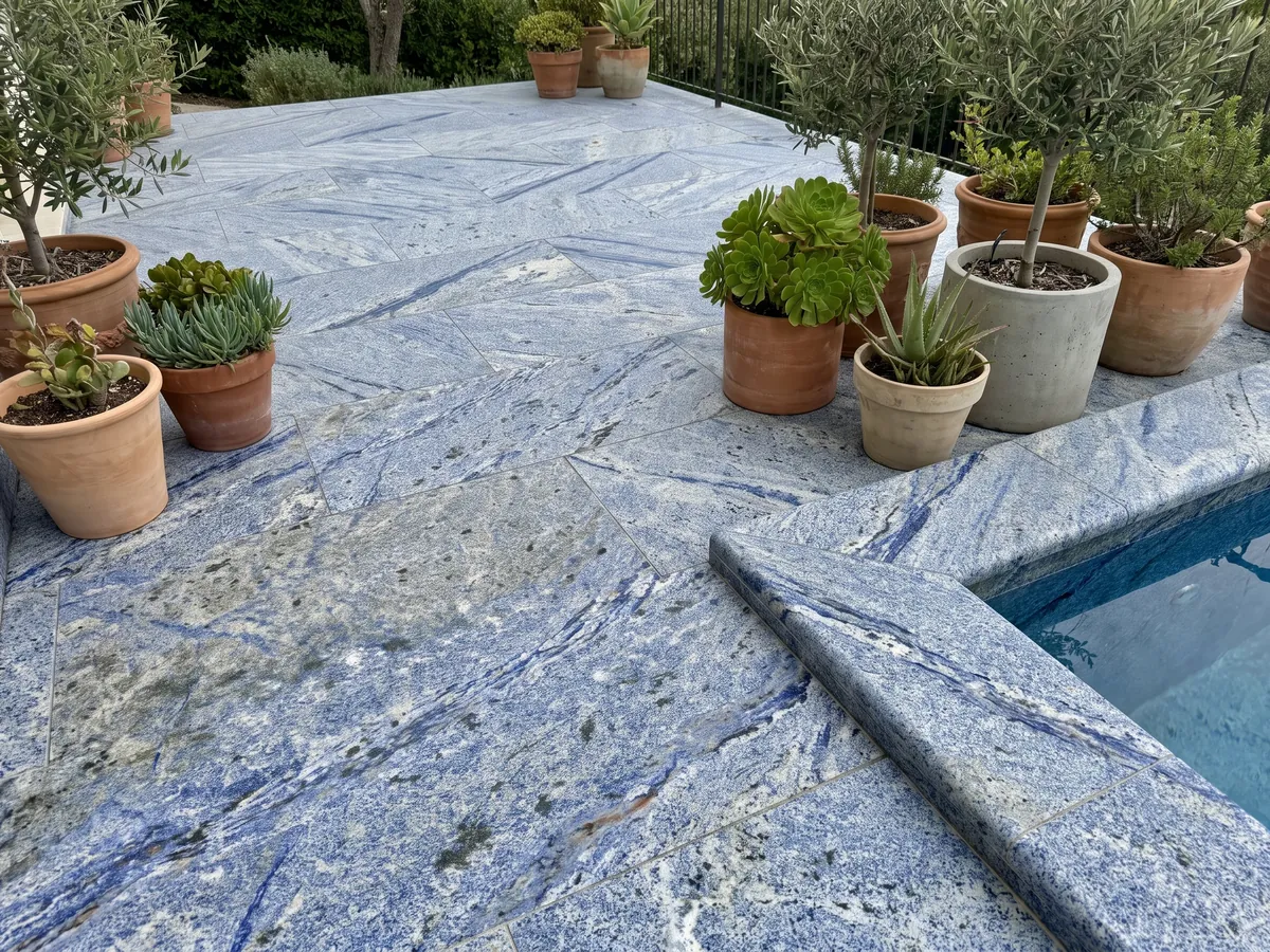 Terrace floor and pool edge in Azul Bahia Granite with planters: deep granular blue with white areas and dark patches