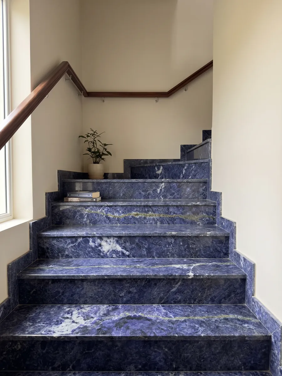 Interior staircase with Jeriba Blue granite steps and a handrail: intense violet blue with white clouds and a golden green line
