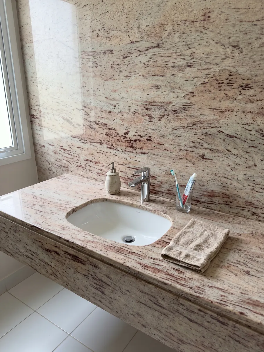 Bathroom vanity top and wall in Ivory Brown beige granite with a white sink and chrome fixtures: ivory with reddish and burgundy horizontal strokes