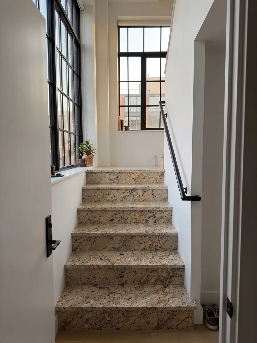 Interior staircase with beige Santa Cecilia granite steps and a handrail: golden beige with burgundy blotches and gold and dark gray veining